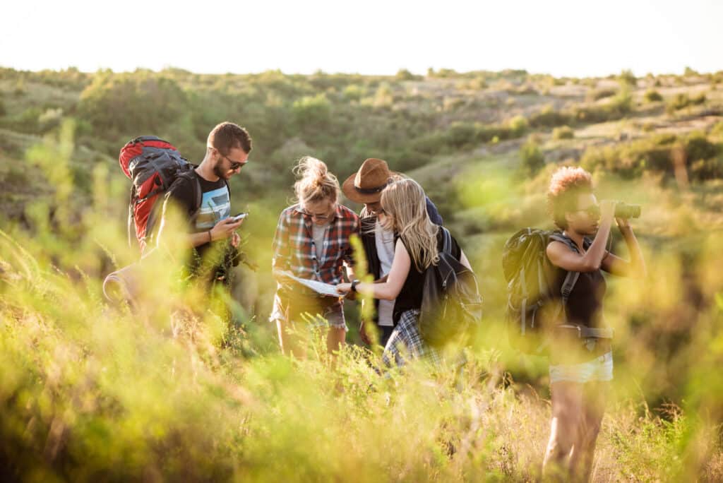 young friends with backpacks enjoying view traveling canyon scaled 1