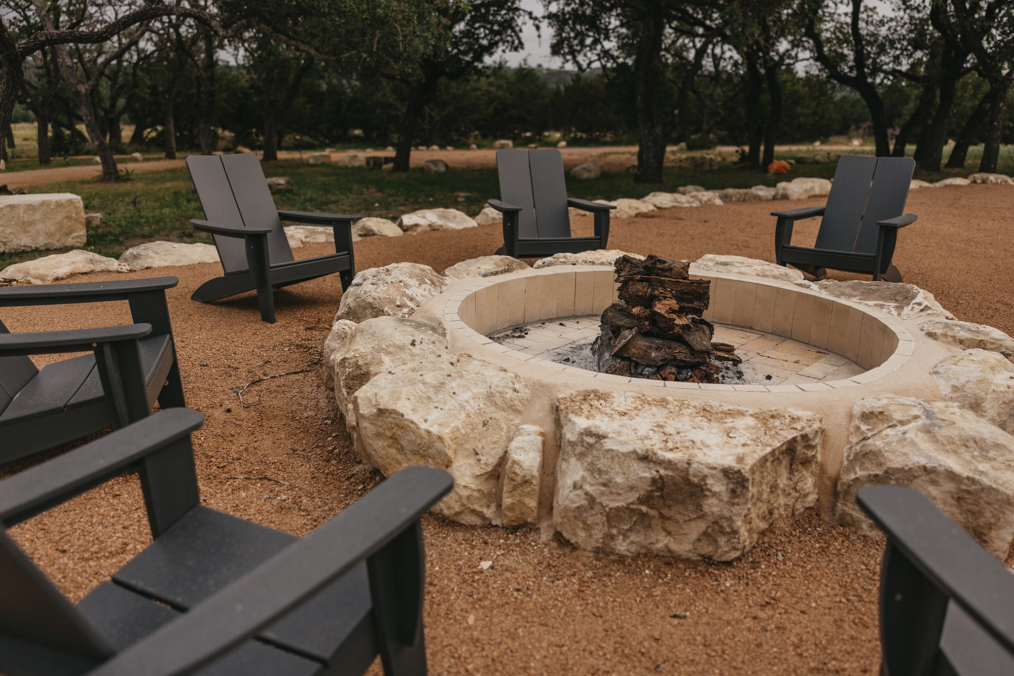 Limestone fire pit with Adirondack chairs at Camp Hideaway — evening gathering space for team retreats
