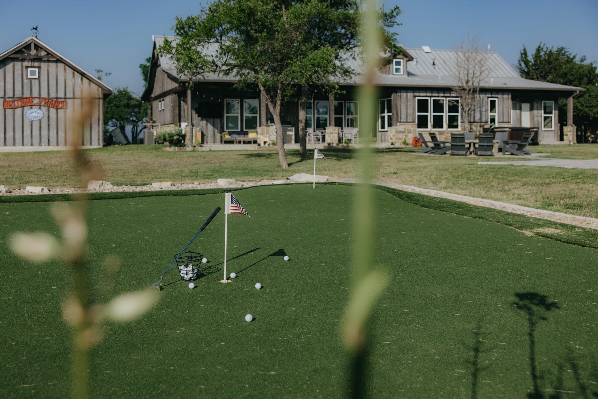 Putting green and outdoor activity area at Camp Hideaway Fredericksburg with Ranch House in background