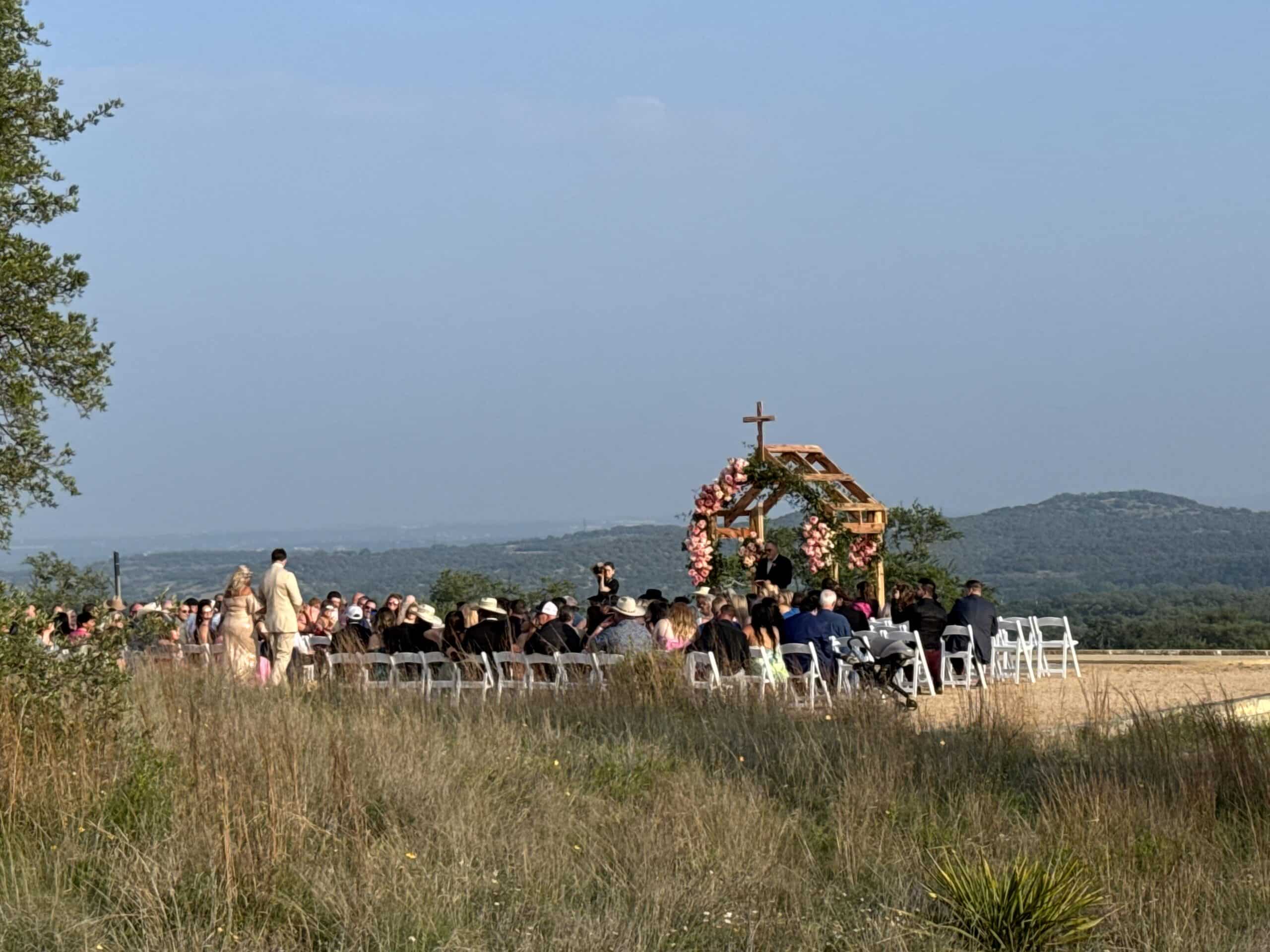 Outdoor ceremony at Camp Hideaway Spicewood showing panoramic Texas Hill Country terrain and rolling cedar-covered hills